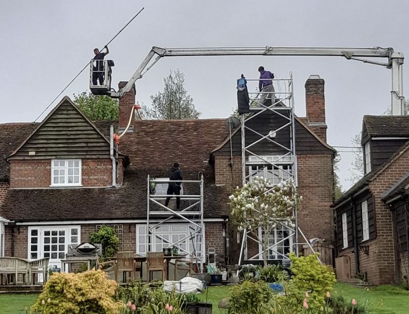 The Moss Cleaners using cherry picker and scaffolding to clean roof safely and professionally in Hindhead, Surrey